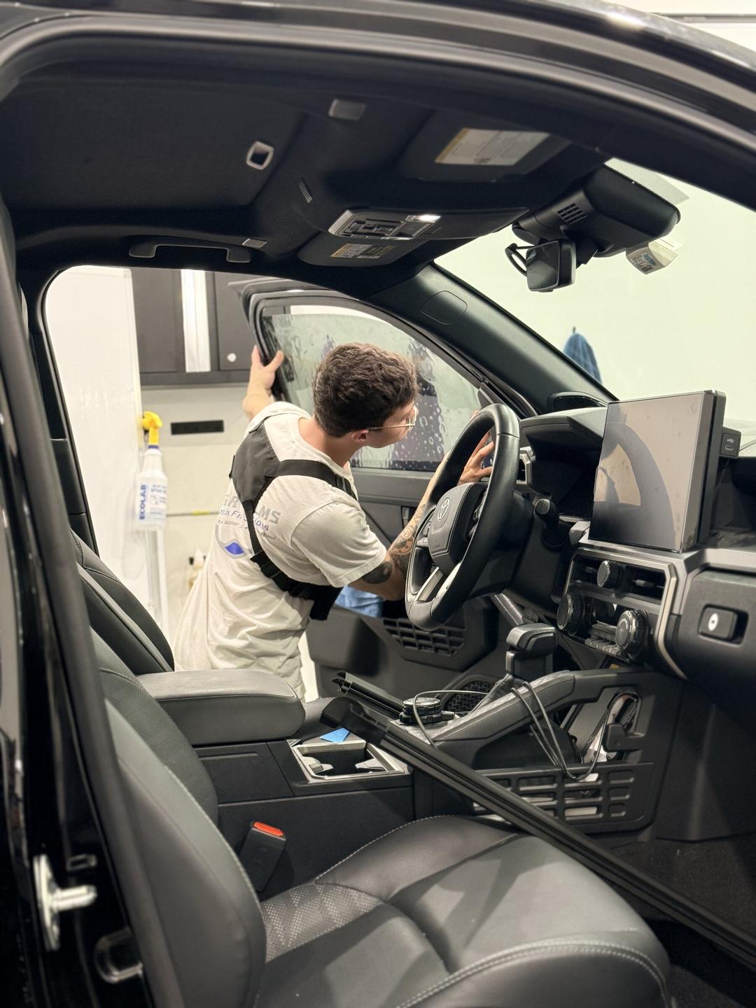 Taggart Films installer working ceramic tint onto a Toyota door from inside the cabin