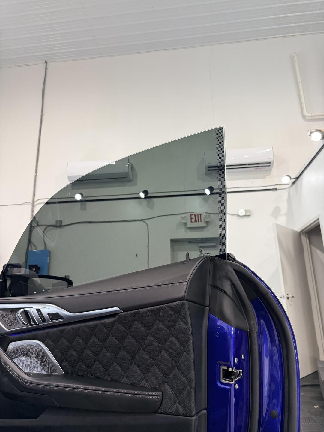 Ceramic-tinted door glass rolled up on a blue BMW during install at Taggart Films